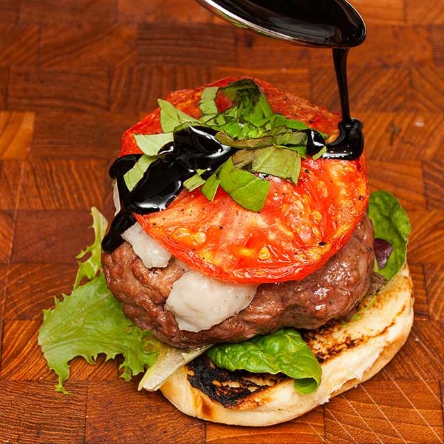 Topping the Mediterranean burger with roasted tomato and balsamic drizzle